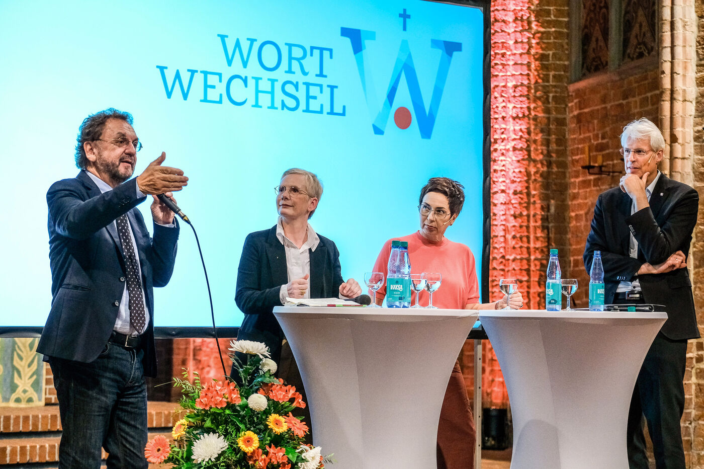 Zwei Männer und zwei Frauen diskutieren in einem Kirchenraum.