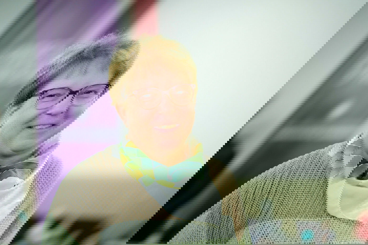 Eine weiblich gelesene Person mit kurzen, blonden Haaren und Brille.