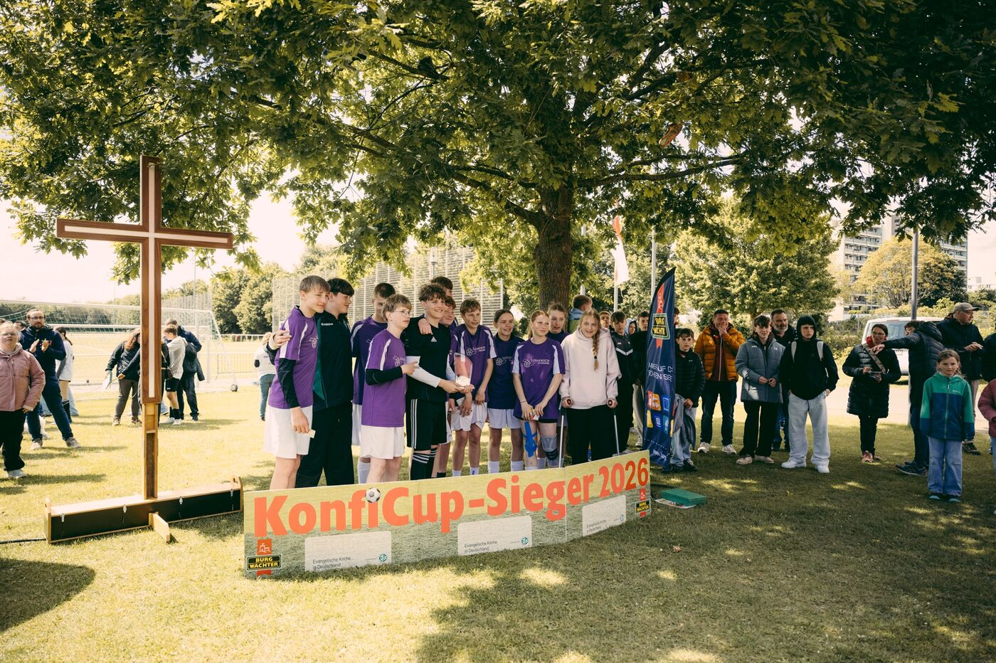 Eine Gruppe junger Menschen posiert hinter einem Banner mit der Aufschrift KonfiCup-Sieger 2026.