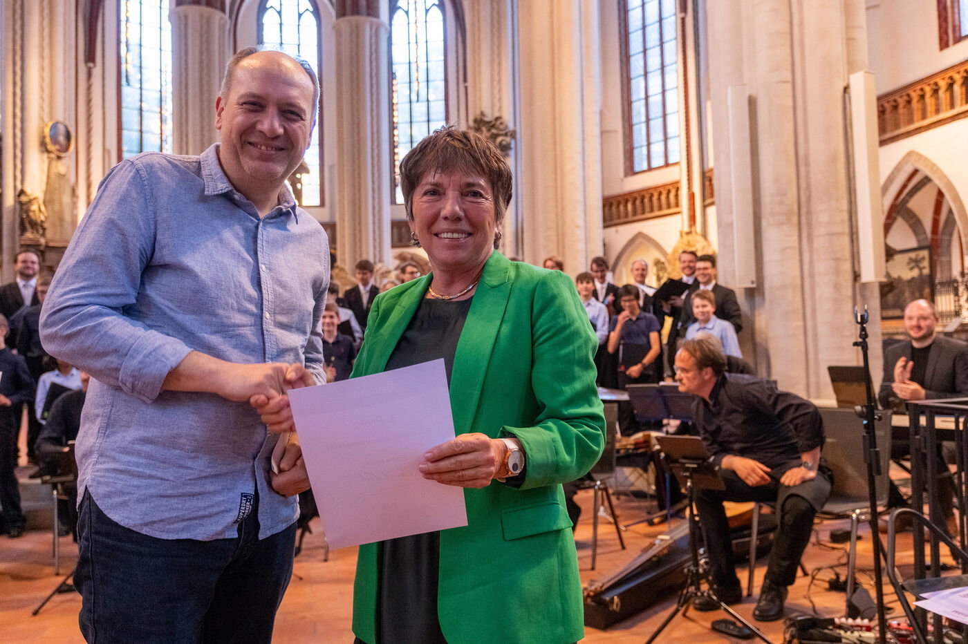 Eine als Mann und eine als Frau lesbare Person in einer Kirche bei einer Preisverleihung.