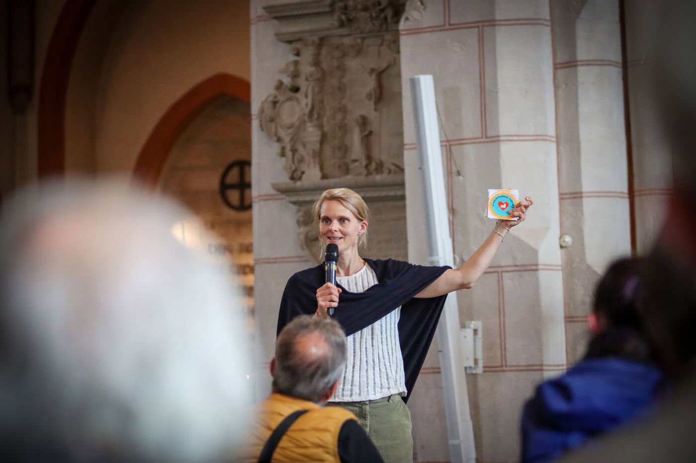Eine als Frau lesbare Person hält eine Karte mit einem Herzen hoch