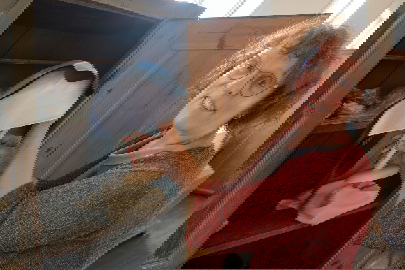 Eine Frau nimmt eine Haube aus einem Schrank.