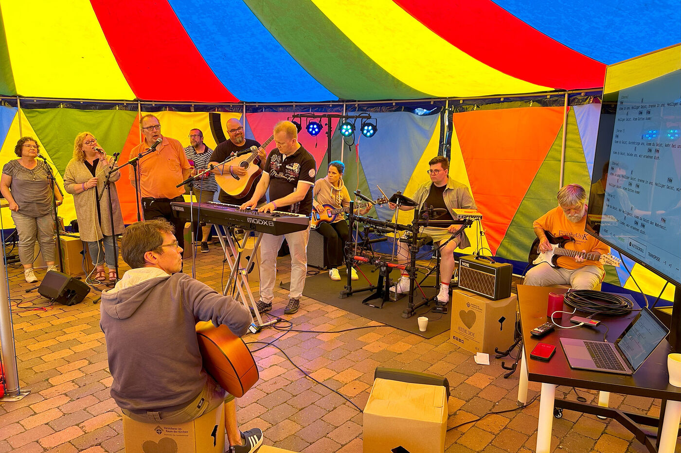 Teilnehmende eines Bandworkshops studieren in einem Zirkuszelt gemeinsam ein Lied ein.