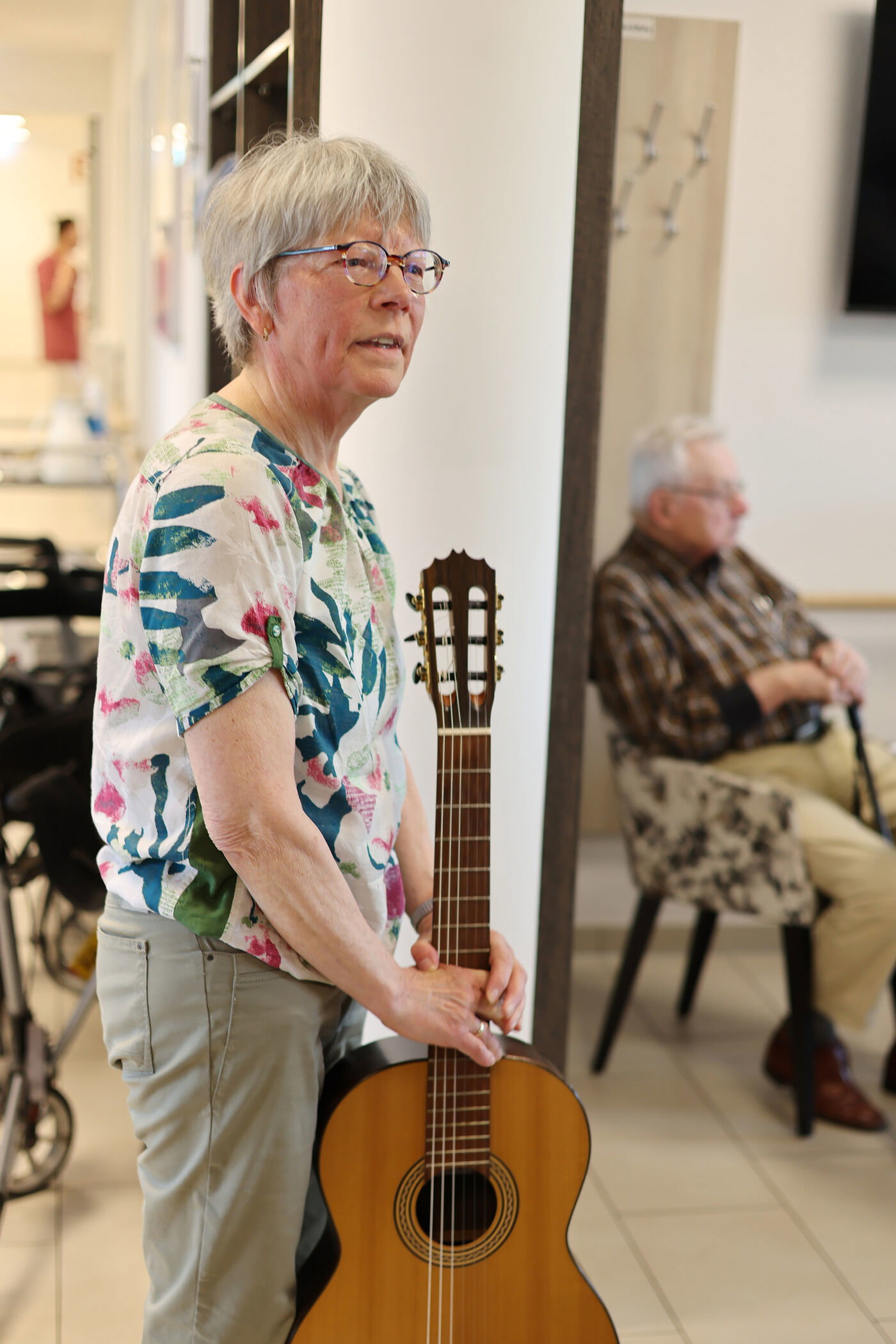 Eine als Frau lesbare Person mit einer Gitarre spricht zu Publikum.