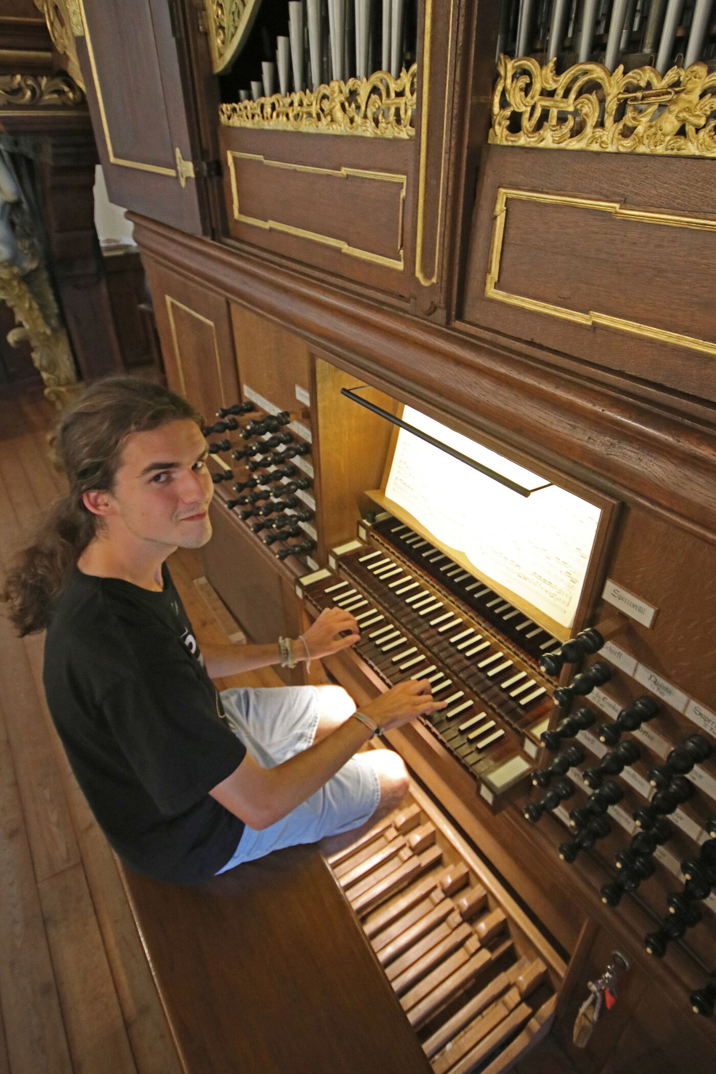 Eine als junger Mann lesbare Person spielt auf einer Orgel.