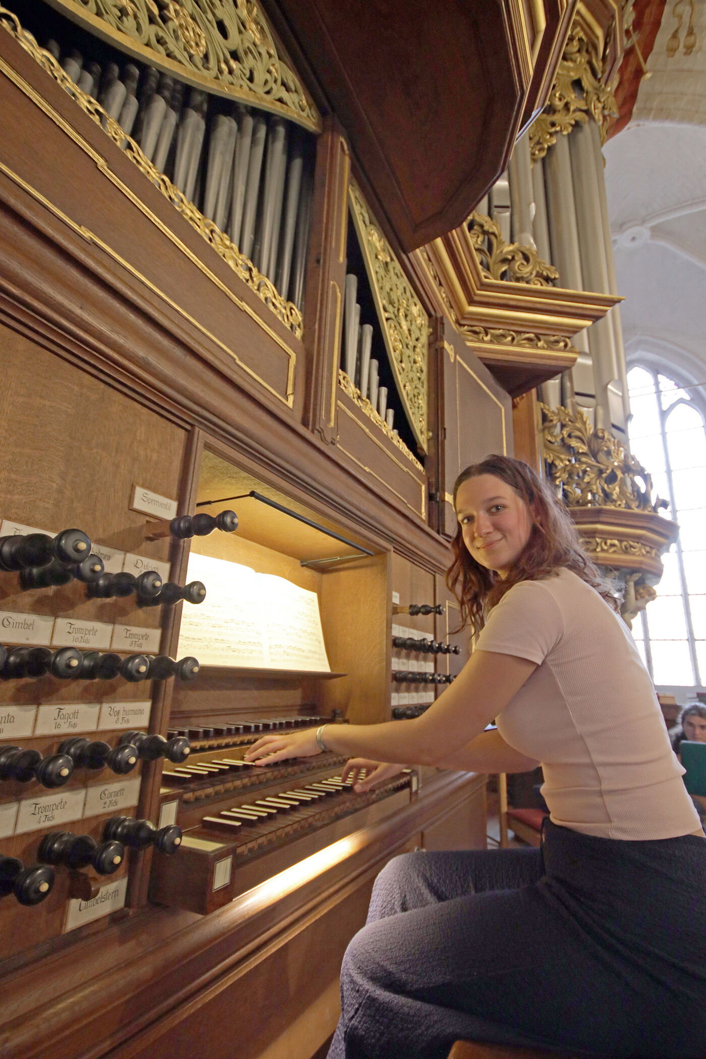 Eine als junge Frau lesbare Person spielt auf einer Orgel.