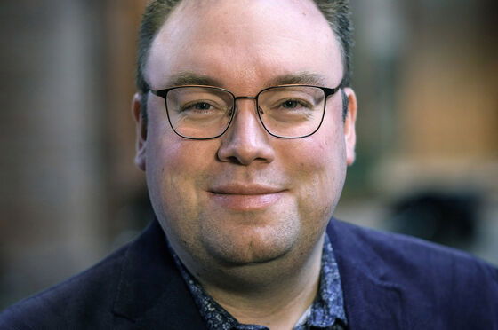 Eine männlich zu lesende Person mit Brille schaut in die Kamera.