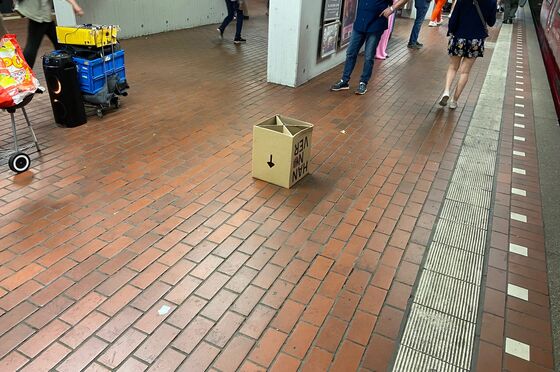 auf einem Bahnsteig liegt ein Papphocker, auf dem ein Pfeil statt nach oben nach unten zeigt. 