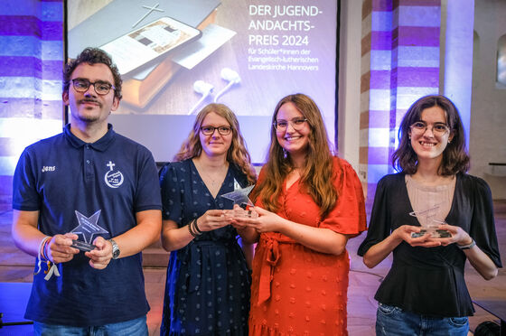 Vier junge Menschen posieren bei einer Preisverleihung mit einem Pokal.