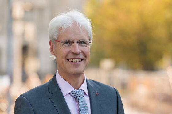 Eine männlich gelesene Person mit kurzen weißgrauen Haaren und Brille. 