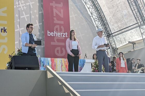 Drei Menschen stehen auf einer Bühne.