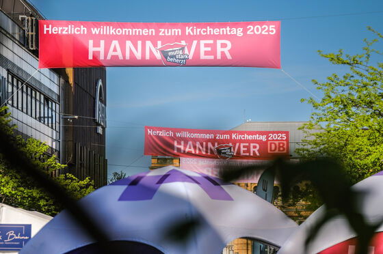 Ein Banner mit dem Kirchentagsschriftzug hängt über einer Straße.