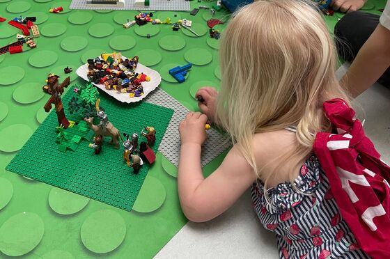 Ein Kind liegt auf dem Boden uns spielt mit Legosteinen.