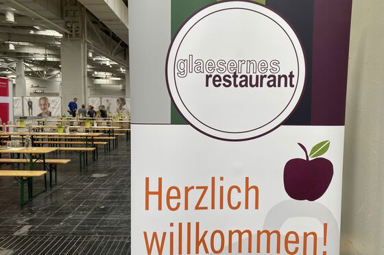 Ein Schild am Eingang des gläsernen Restaurants mit der Aufschrift Herzlich Willkommen.
