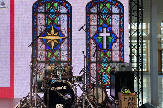 Vor zwei bunten Kirchenfenstern steht ein Schlagzeug.