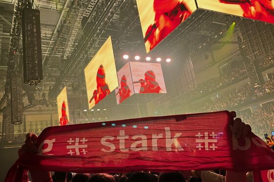 Vor eine bunt angestrahlte Bühne wird ein Schal mit der Aufschrift stark gehalten.