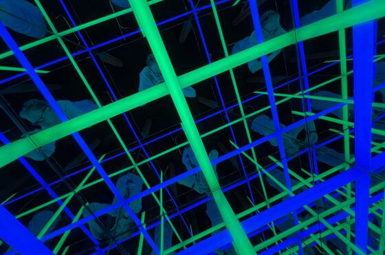 blaue und grüne Neon-Strahlen durchkreuzen einen dunklen Raum