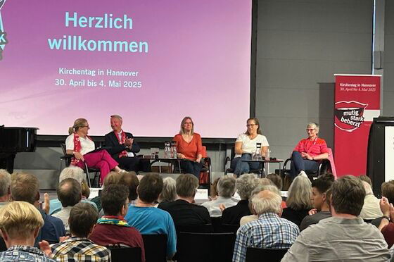 Mehrere Menschen auf einer Bühne vor Publikum.