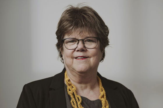 Eine als Frau lesbare Person mit Halstuch und Brille