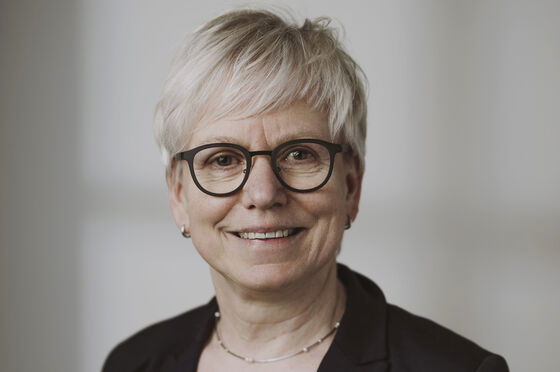 Eine als Frau lesbare Person mit Brille und grauen Haaren