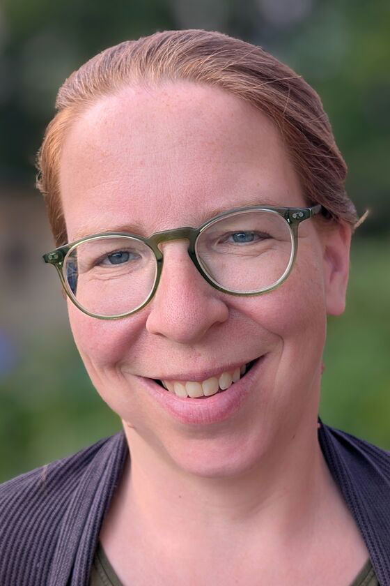 Ein weiblich zu lesende Person mit Brille lächelt.