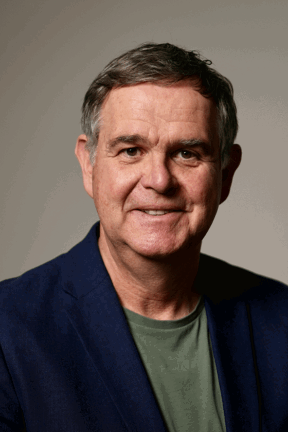 Eine männlich gelesene Person mit kurzen Haaren und blauem Jackett.