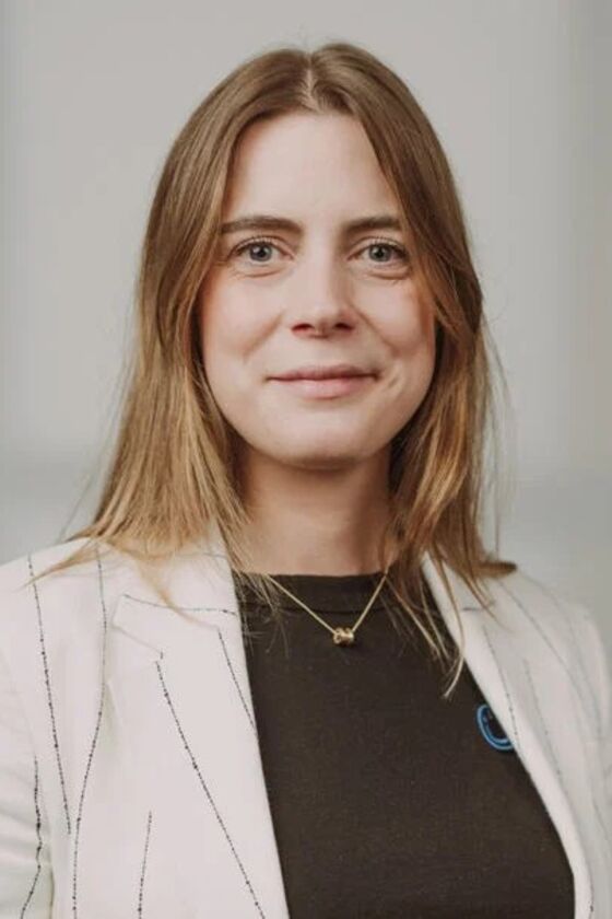 Eine junge als Frau lesbare Person mit schulterlangen braunen Haaren.