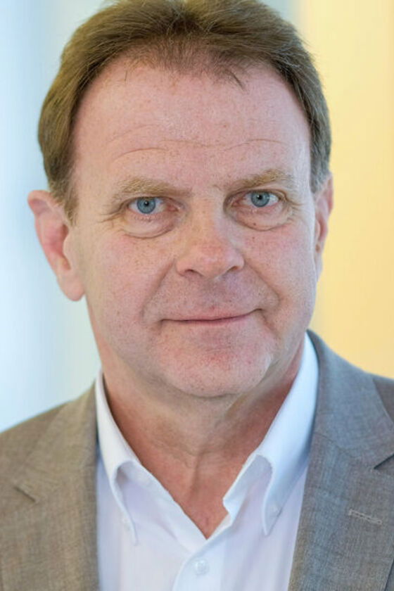 Ein mittelalter Mann mit weißem Hemd und grauem Sakko.