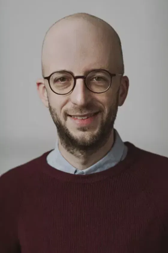 Eine männlich gelesene Person mit dunklem Bart und mit Brille. 