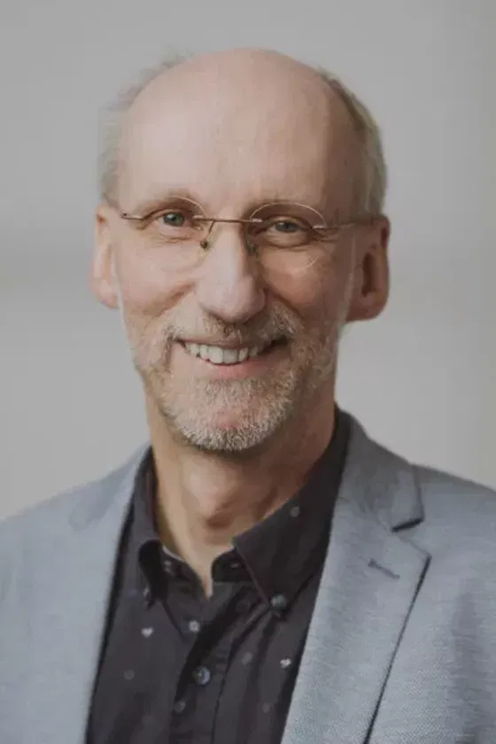 Eine männlich gelesene Person mit kurzem hellen Bart und einer Brille. 