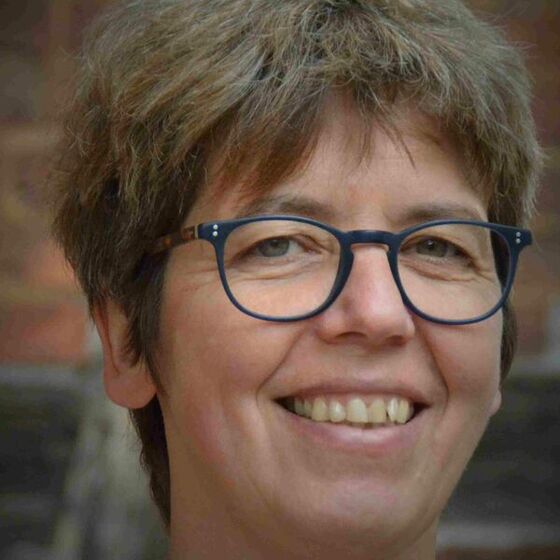 Nahaufnahme einer Frau mit kurzen Haaren und Brille.