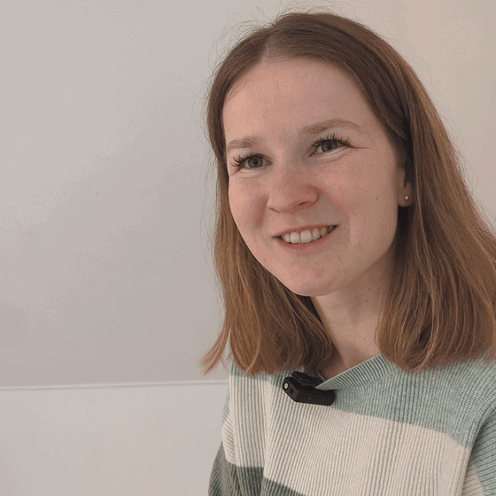 Eine weiblich gelesene Person mit mittellangen, mittelblonden Haaren.