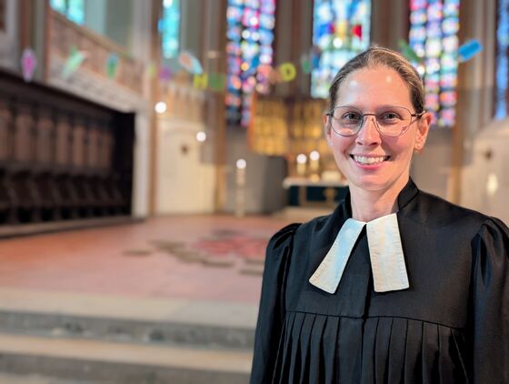 Eine Pastorin in einer hell erleuchteten und geschmückten Kirche.