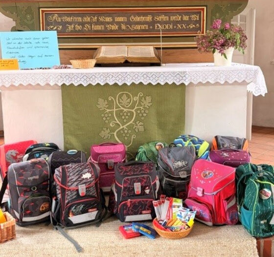 Vor einem Altar in einer Kirche stehen mehrere Schulranzen.