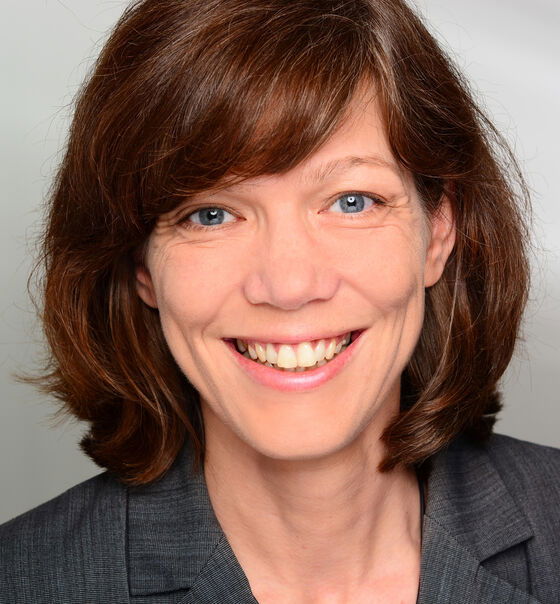 Eine als Frau lesbare Person lächelt in die Kamera.