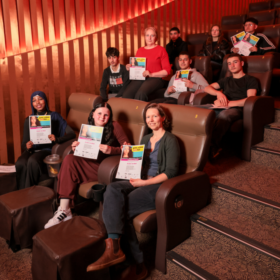 Mehrere junge Menschen sitzen in Kinoreihen.