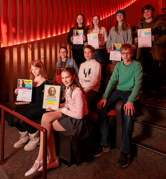 Mehrere junge Menschen sitzen in Kinoreihen.