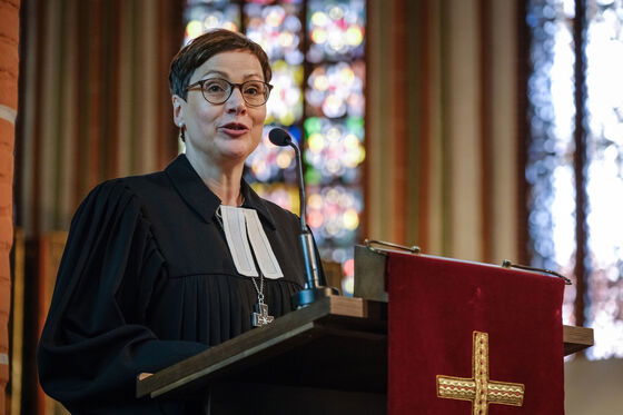 Eine weiblich zu lesende Person im Talar steht an einem Redepult.