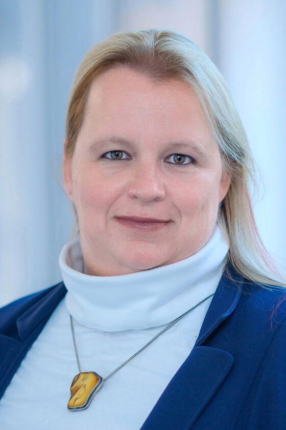 Eine Frau mit hellblauem Pullover und schulterlangen blonden Haaren schaut in die Kamera.