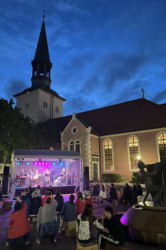 Ein abendliches Konzert auf einer Open-Air-Bühne vor einer Kirche