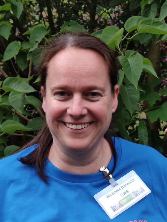 Eine als Frau lesbare Perso mit blauem T-Shirt und einem Namensschild mit der Aufschrift: Michaela Bärwaldt GWS.