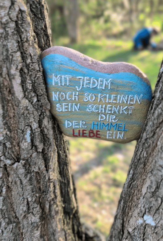 Ein zwischen zwei Ästen eingeklemmter Stein mit der Aufschrift: Mit jedem noch so kleinen Sein schenkt dir der Himmel Liebe ein.
