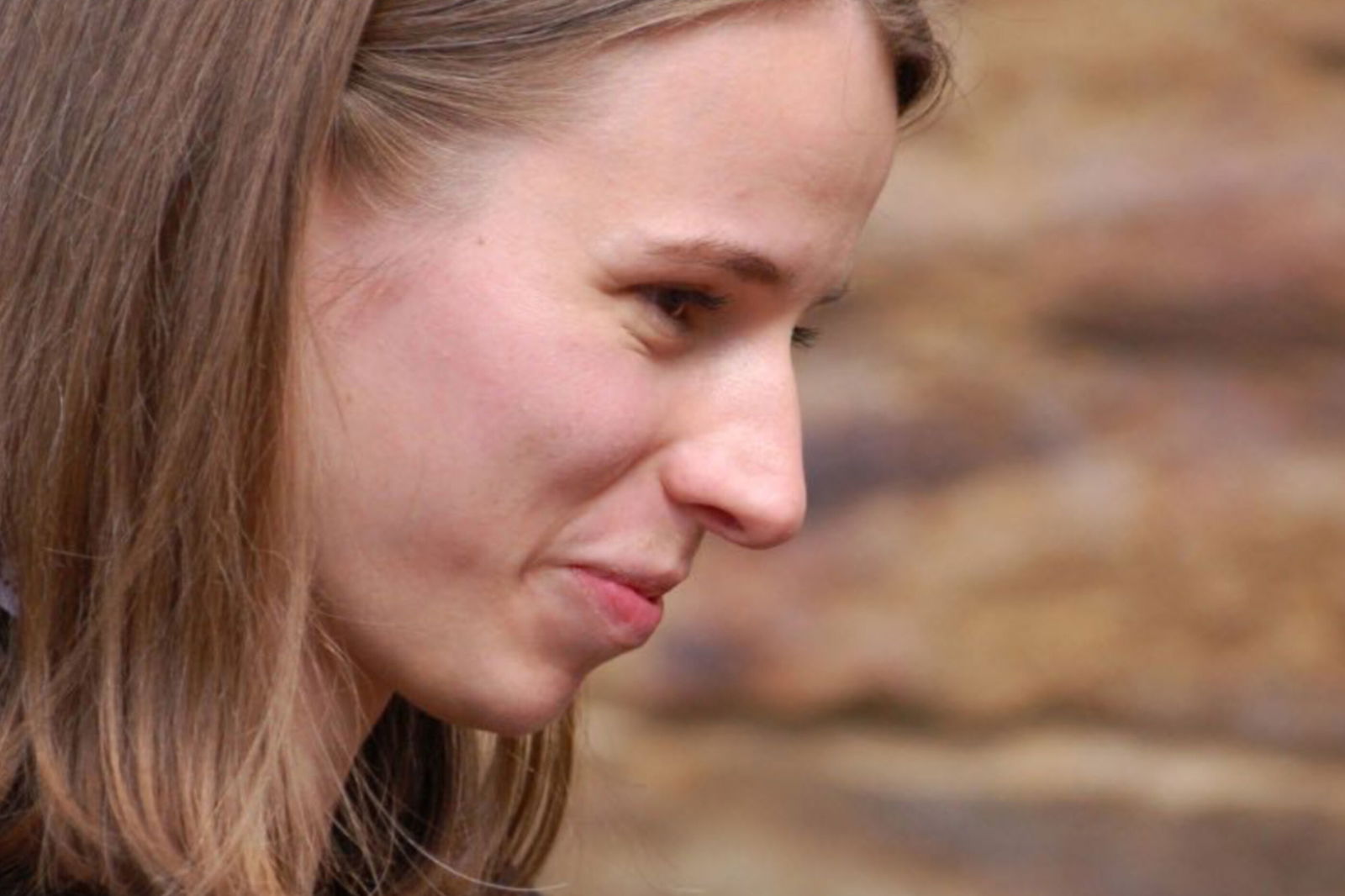 Ein junge Frau mit braunen Haaren neigt den Kopf