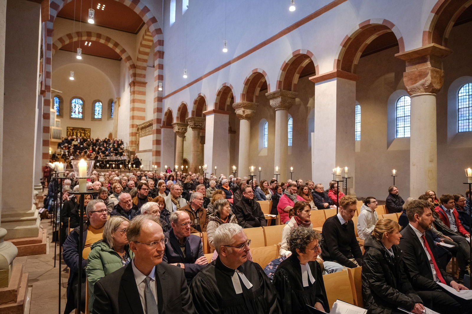 Blick in eine romanische Kirche, die voll besetzt ist.