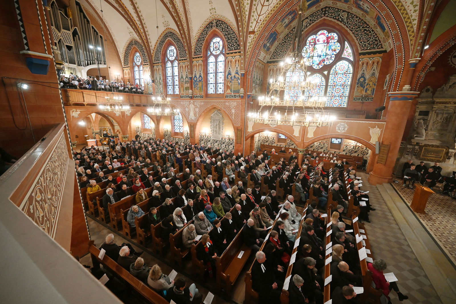 Blick von der Seite oben in ein Kirchenschiff, in dem in den Bankreihen viele hundert Menschen sitzen.