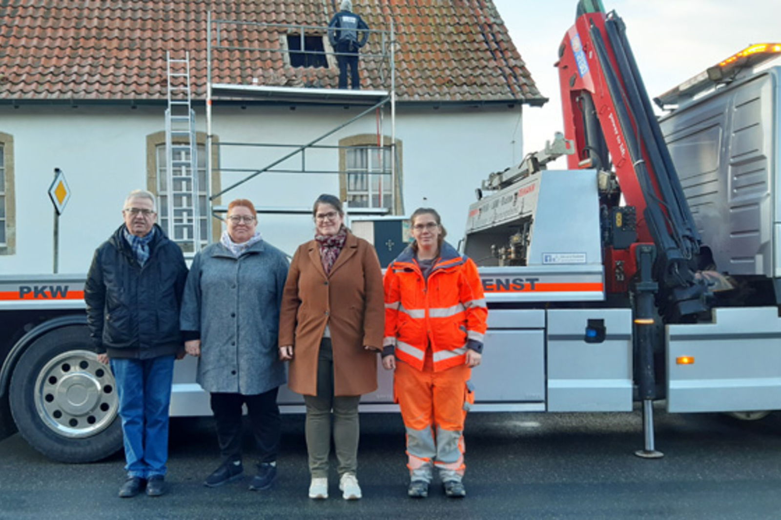 Eine Gruppe Menschen vor einem Gerüst und einem Auto. 