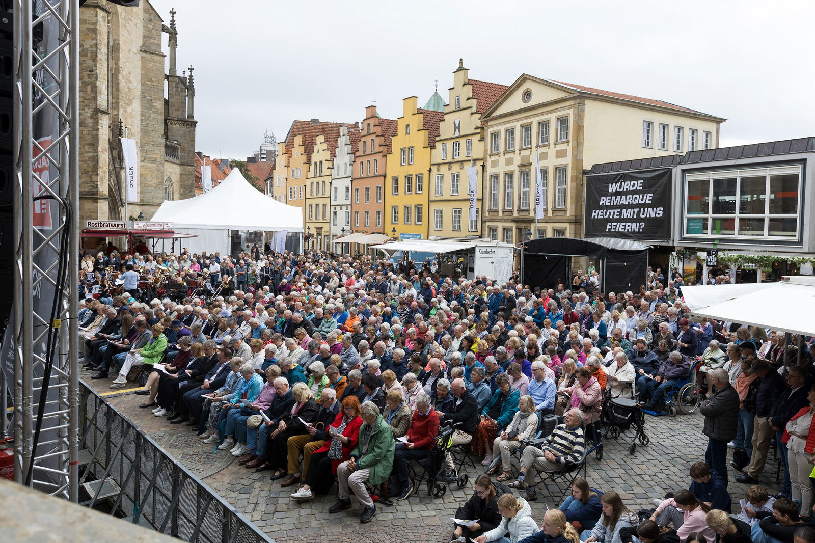 Eine große Menschenmenge vor einer Bühne auf einem öffentlichen Platz.