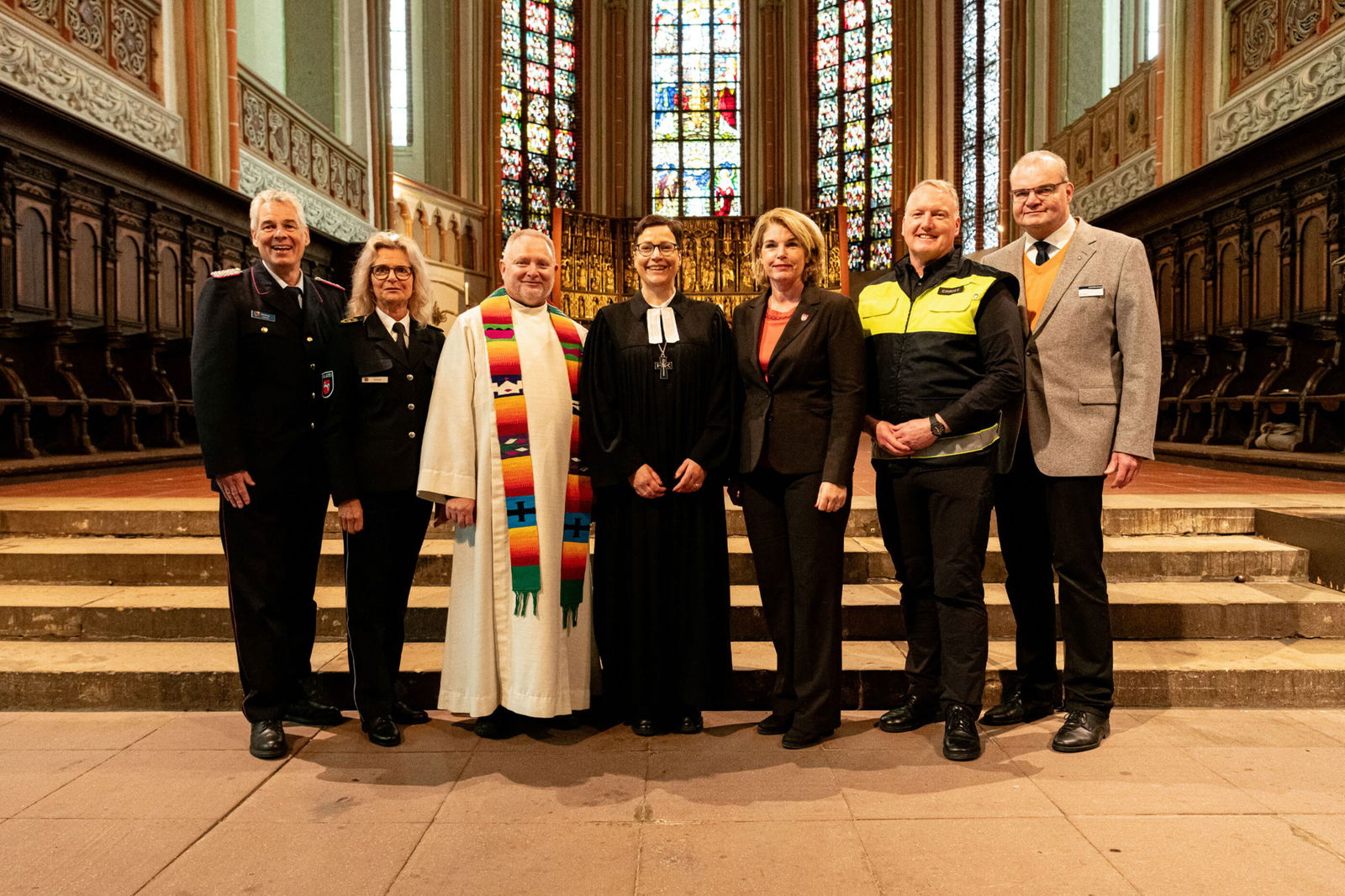 Sieben Personen stehen zusammen in einer Kirche.