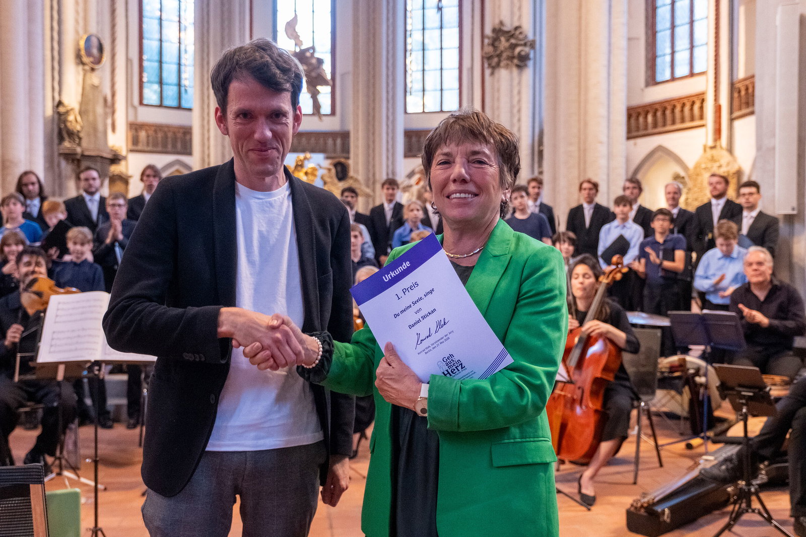 Eine als Mann und eine als Frau lesbare Person in einer Kirche bei einer Preisverleihung.