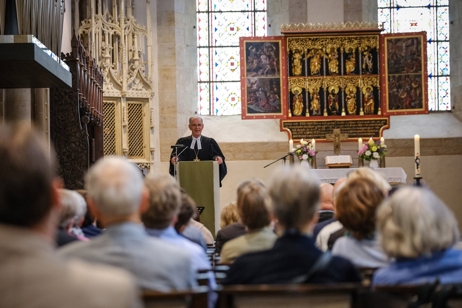 Die Klosterkirche Loccum ist von innen zu sehen. Im Fokus steht Landesbischof Ralf Meister hinter einem Redepult. Die Gottesdienstgemeinde ist von hinten unscharf zu erkennen.